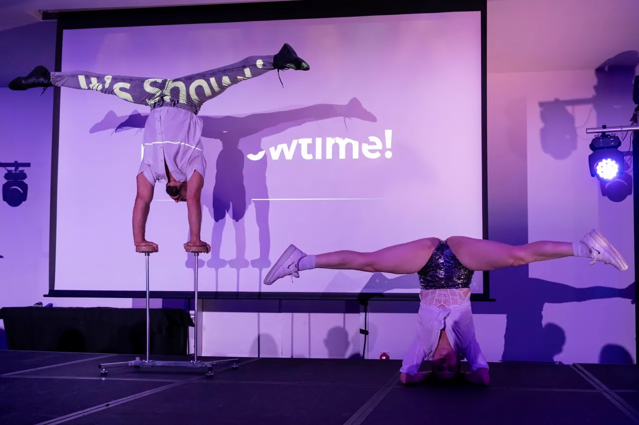 Acrobat in a one-arm handstand on canes at a corporate event