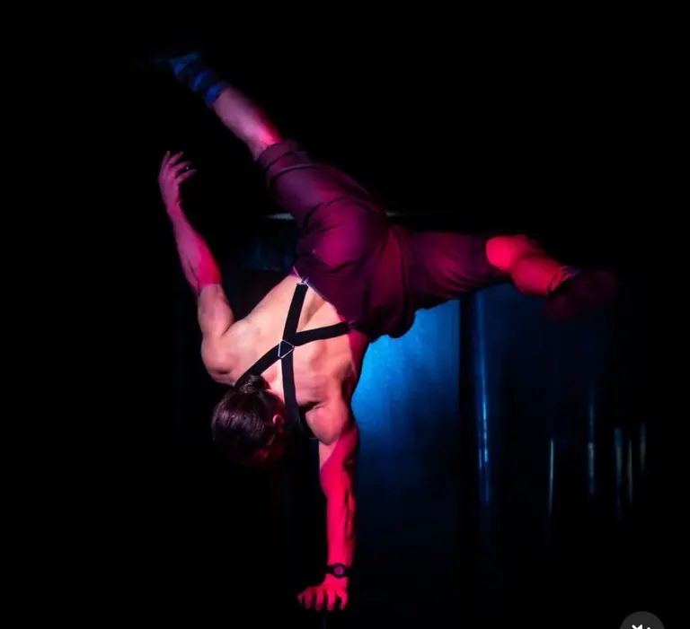 Aerial straps artist mid-figure in purple light