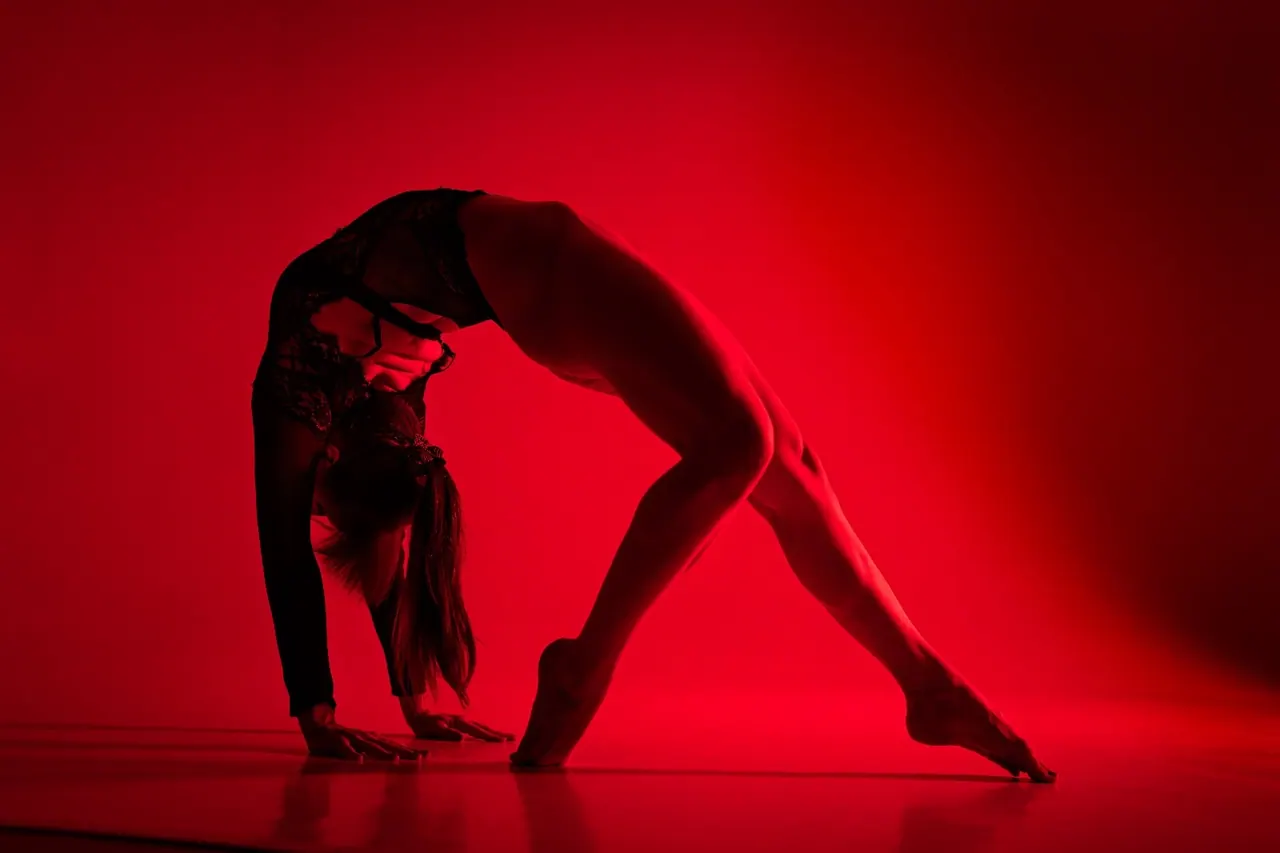 Contemporary dancer in a backbend under red light