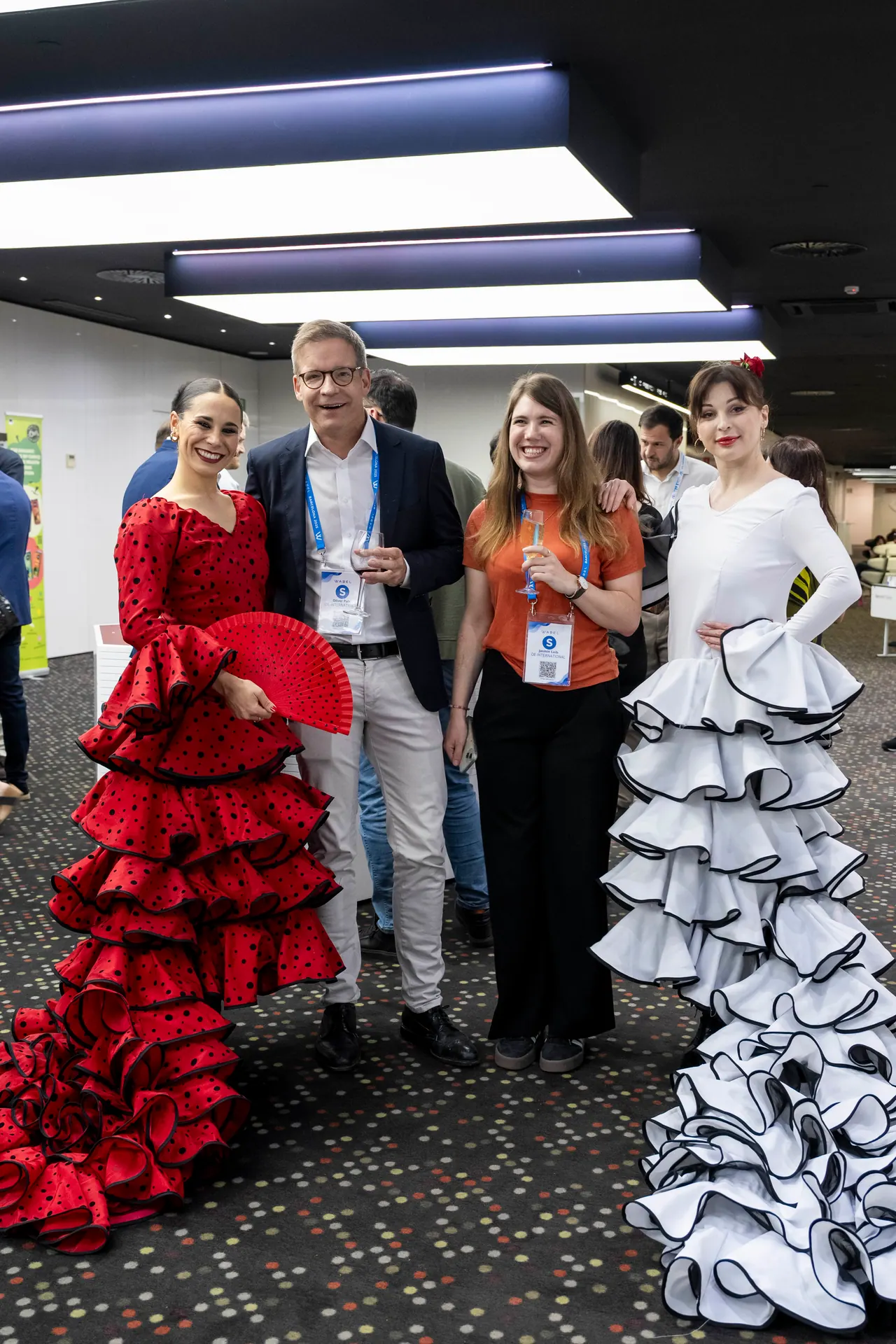 Flamenco dancers in red and white dresses posing with event guests