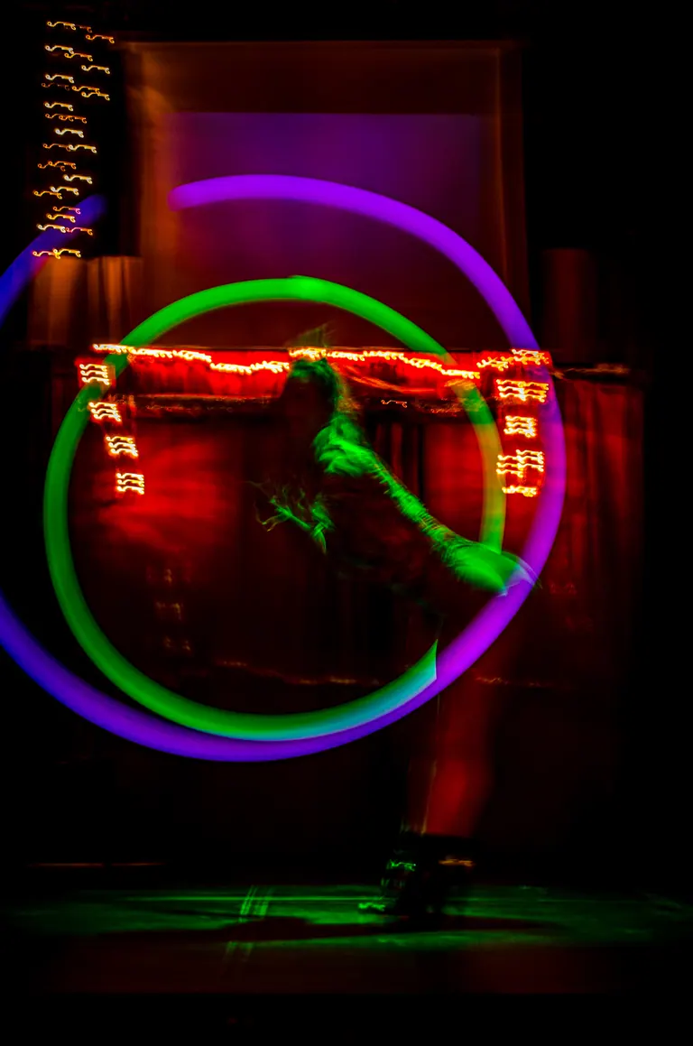 Long exposure of a performer drawing light trails with LED hoops