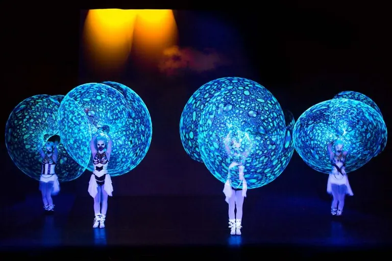 Performers spinning illuminated LED orbs in a dark venue