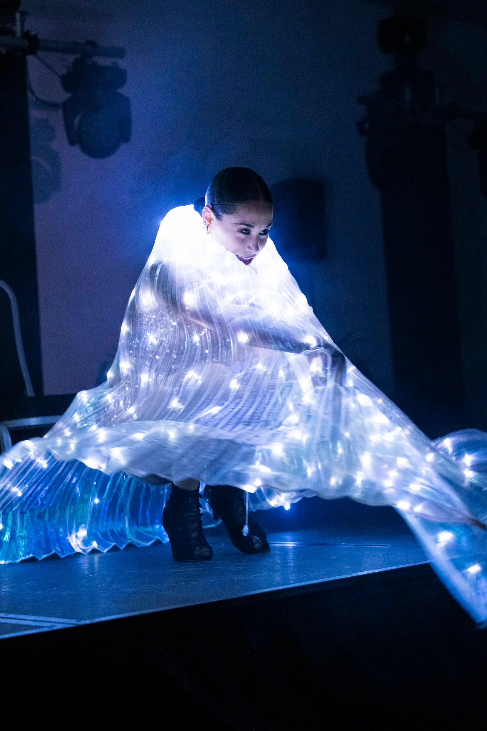 Dancer performing with illuminated LED wings on a gala stage
